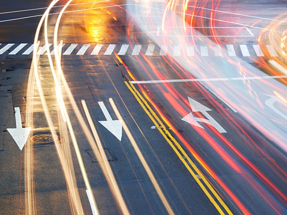 photograph of multiple laned road with light trials from passing cars headlights 